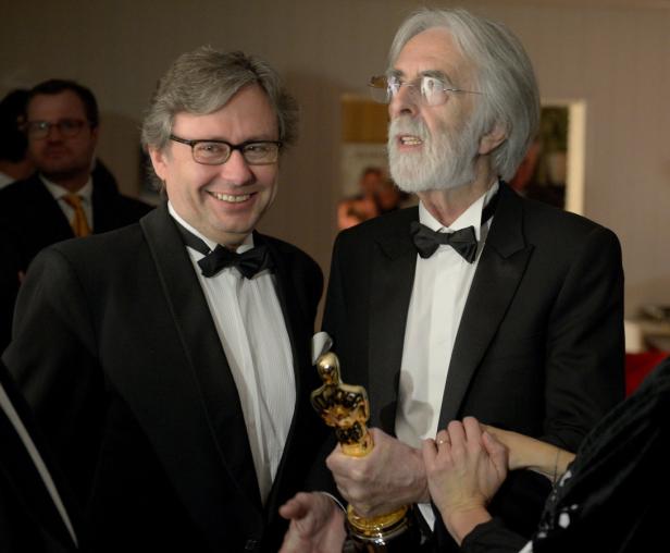 Zwei Männer in Anzügen halten eine Oscar-Statue.