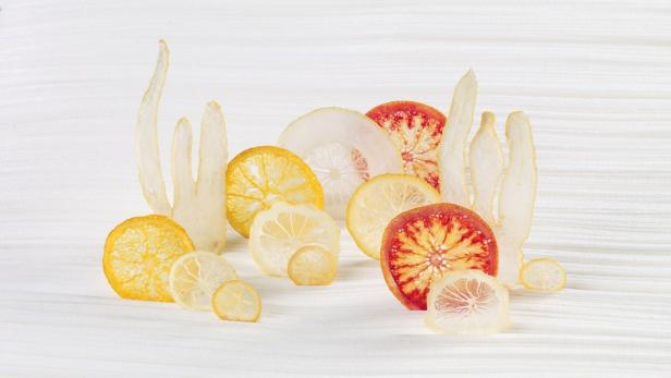 Getrocknete Zitronen-, Orangen- und Grapefruitscheiben auf einem weißen Untergrund.