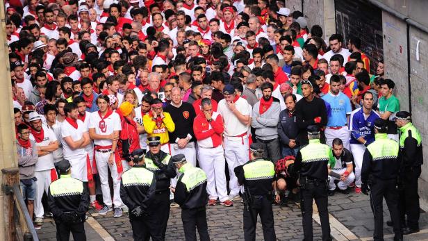 Eine Menschenmenge in Pamplona, viele tragen traditionelle weiße Kleidung mit roten Schärpen.