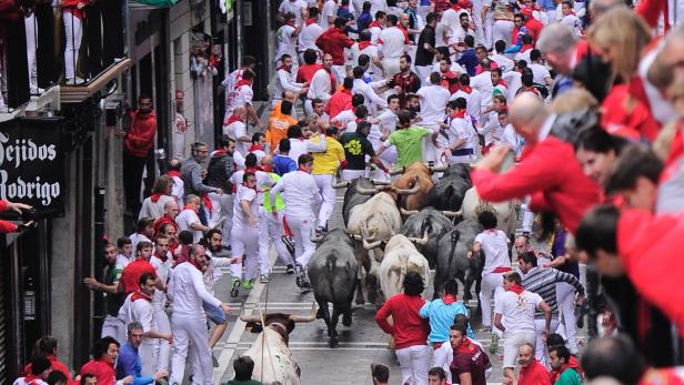 Beim San Fermín-Fest rennen Menschen vor einer Gruppe Stiere durch die Straßen von Pamplona.
