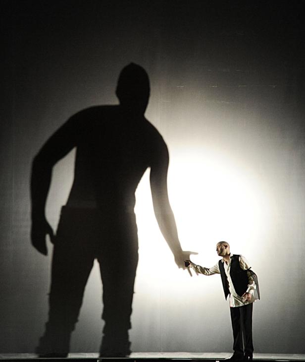 Ein Mann streckt seine Hand nach dem Schatten einer anderen Person aus.