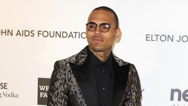 Chris Brown trägt eine gemusterte Jacke und eine Brille.