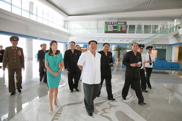 Kim Jong-un und seine Frau Ri Sol-ju gehen mit anderen Würdenträgern durch einen Flughafen.
