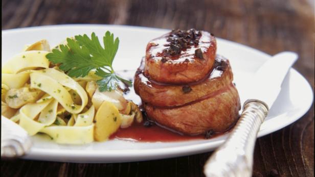 Ein Teller mit Medaillons vom Rind, Bandnudeln und einer Sauce.