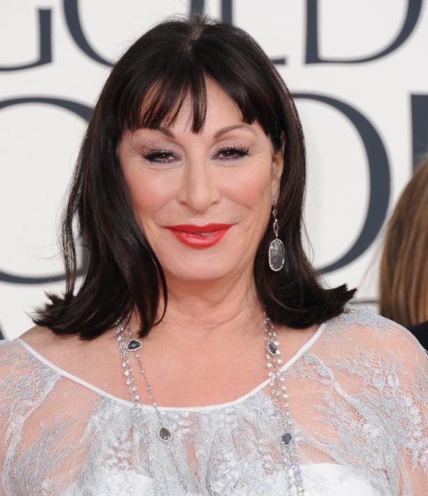Anjelica Huston mit dunklen Haaren, rotem Lippenstift und einer langen Halskette.