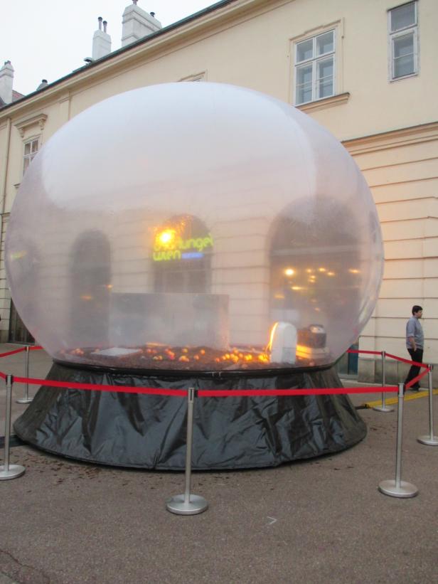 Eine große, transparente Kugel mit der Aufschrift „Dschungel Wien“ steht im Freien.