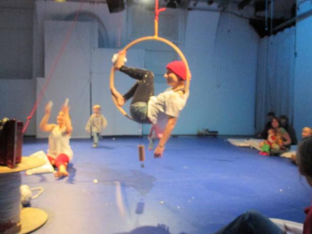 Eine Frau turnt in einem Reifen, während andere Personen zusehen.