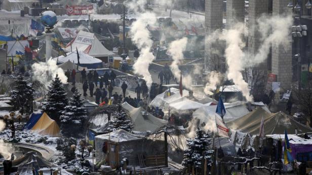 Eine verschneite Zeltstadt mit Rauchwolken und Menschenansammlungen.