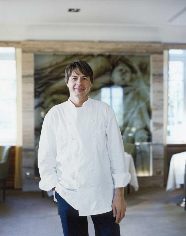 Ein Koch in seiner Arbeitskleidung steht in einem Restaurant.