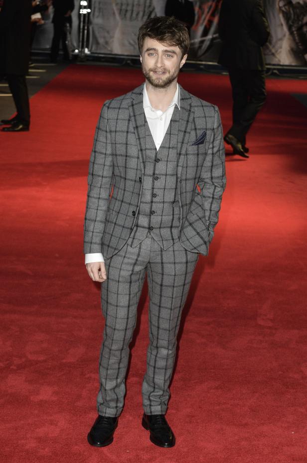 Daniel Radcliffe auf einem roten Teppich in einem grauen Anzug.