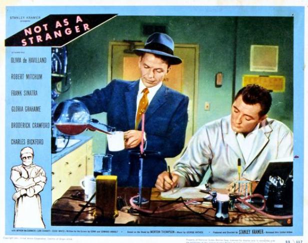 Frank Sinatra gießt in „Not as a Stranger“ eine Flüssigkeit ein, während Robert Mitchum Notizen macht.