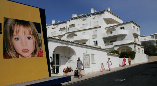 FILE PHOTO - People walk near a billboard at Praia da Luz tourist resort