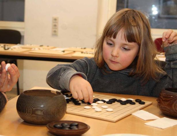 Ein junges Mädchen spielt das Brettspiel Go.