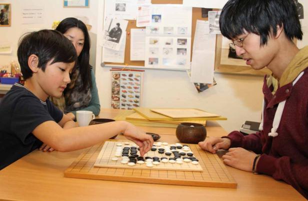 Zwei junge Leute spielen Go, ein strategisches Brettspiel.