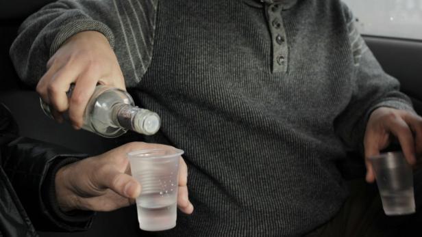 Eine Person gießt eine klare Flüssigkeit aus einer Flasche in einen Plastikbecher.