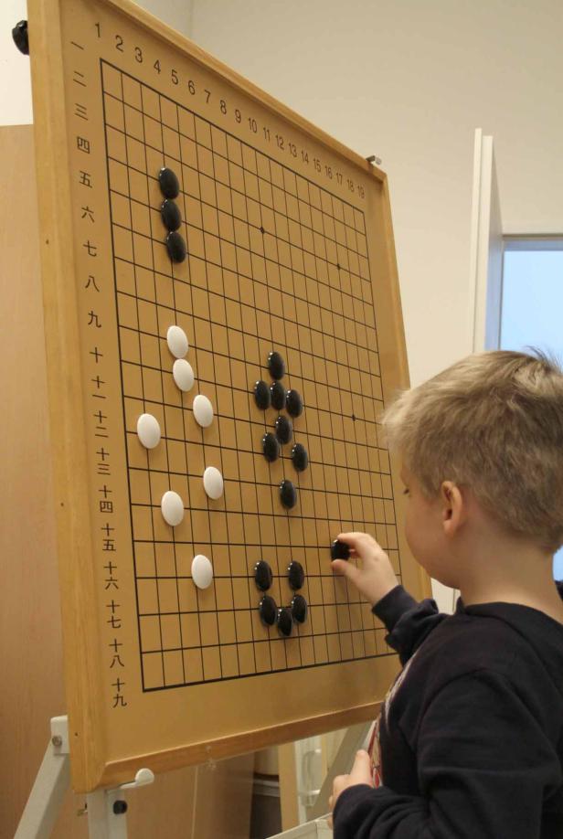 Ein Junge spielt das Brettspiel Go mit schwarzen und weißen Steinen.