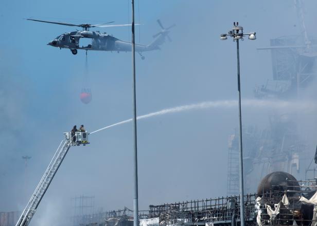U.S. Navy helicopters and city firefighters continue fighting a fire on the amphibious assault ship USS Bonhomme Richard at Naval Base San Diego