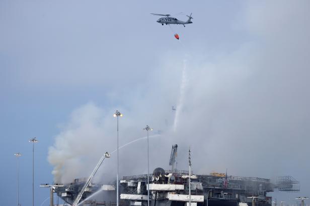 U.S. Navy helicopters and city firefighters continue fighting a fire on the amphibious assault ship USS Bonhomme Richard at Naval Base San Diego