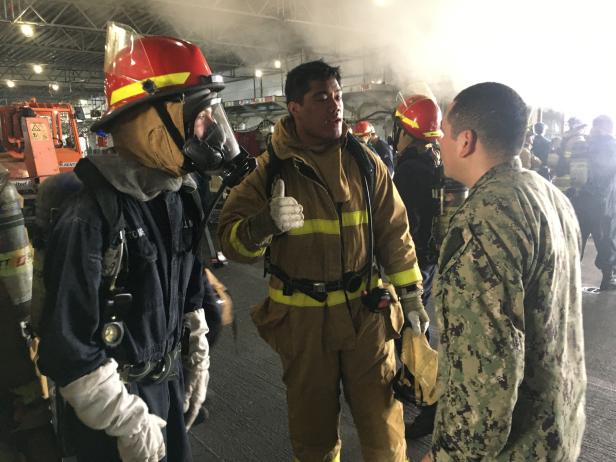 Sailors aboard the U.S. Navy amphibious assault ship USS Bonhomme Richard discuss a fire aboard the ship at Naval Station San Diego