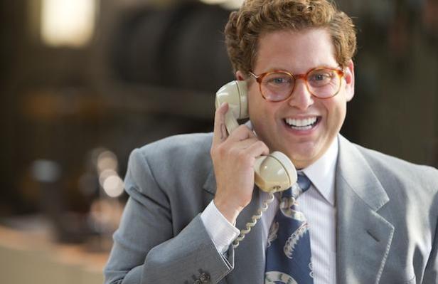 Jonah Hill lächelt in seiner Rolle in „The Wolf of Wall Street“ am Telefon.
