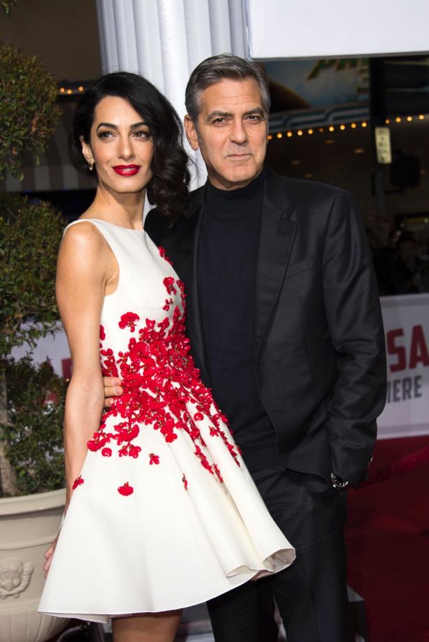 Amal Clooney und George Clooney posieren auf dem roten Teppich.