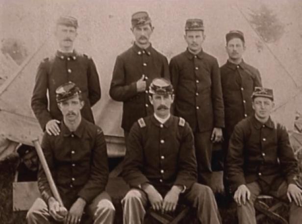 Eine Gruppe von sieben Soldaten in Uniform posiert vor einem Zelt.