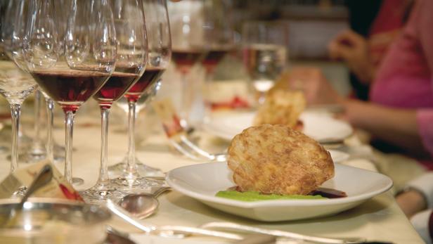 Ein gedeckter Tisch mit Speisen, Wein und Besteck für eine festliche Mahlzeit.