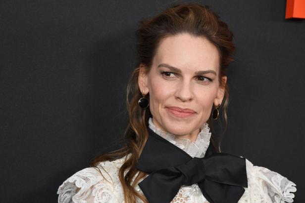 Hilary Swank mit einem weißen Spitzenoberteil und einer schwarzen Schleife.