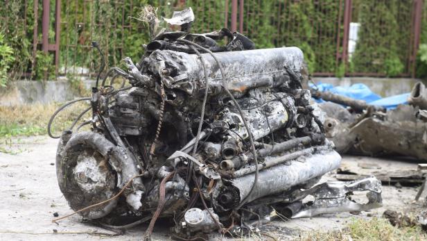 Ein zerstörter und verkohlter Flugzeugmotor liegt auf dem Boden.