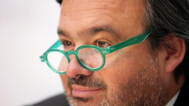 Ein Mann mit Bart und grüner Brille blickt zur Seite.