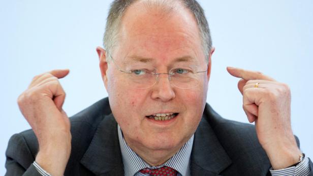 Ein Mann mit Brille gestikuliert mit beiden Zeigefingern in Richtung seiner Schläfen.