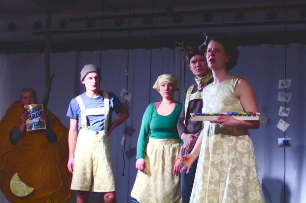 Eine Gruppe von Schauspielern steht auf einer Bühne, eine Frau hält ein Xylophon.