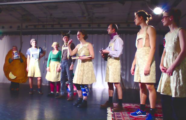 Eine Gruppe von Darstellern steht auf einer Bühne in Kostümen.