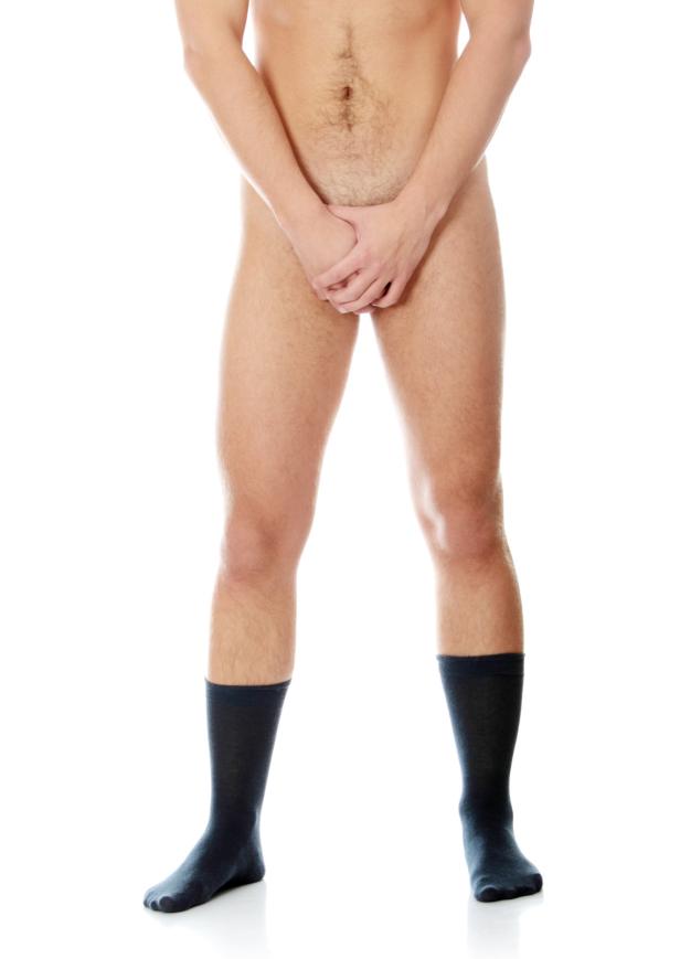 Ein unbekleideter Mann mit schwarzen Socken steht vor einem weißen Hintergrund.