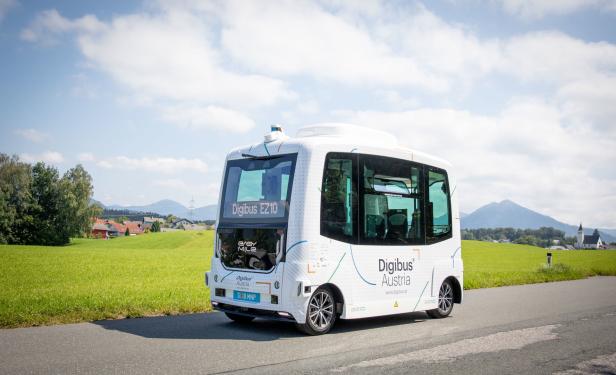 Ein autonomer „Digibus Austria“ auf einer Landstraße vor einer grünen Landschaft.