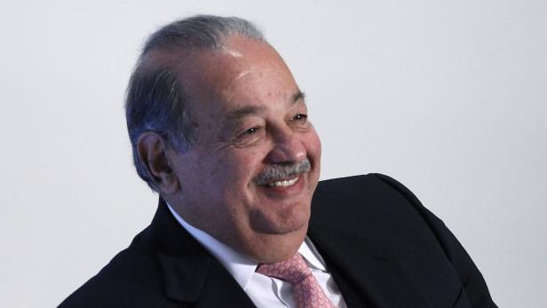 Carlos Slim lächelt in einem dunklen Anzug und einer gemusterten Krawatte.