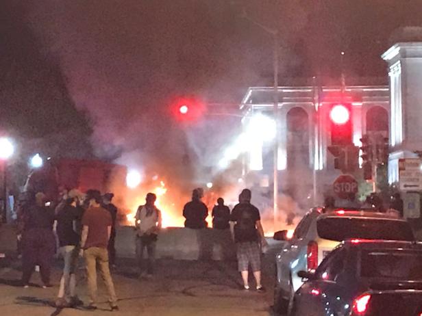 People stand near a burning vehicle in front of the Kenosha County couthouse in Kenosha, Wisconsin