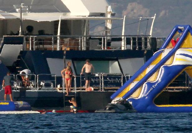 Menschen genießen eine Wasserrutsche an einer Yacht.