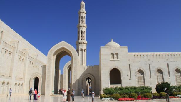 Die Sultan-Qabus-Moschee in Maskat, Oman, mit einem hohen Minarett und verzierten Bögen.