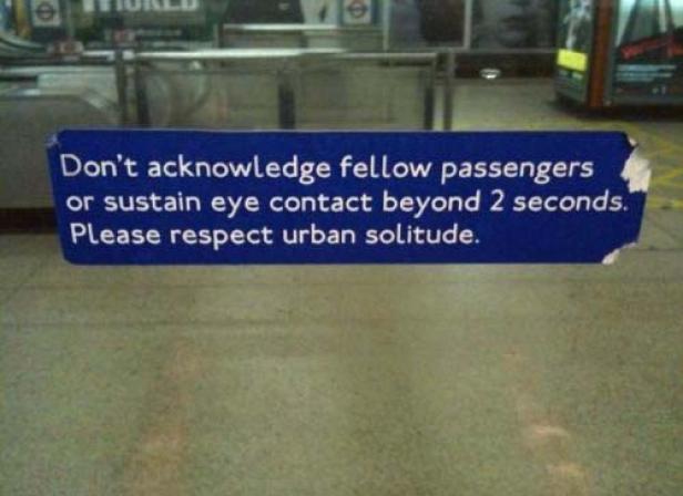 Ein blaues Schild in einer U-Bahn-Station fordert dazu auf, andere Fahrgäste nicht anzuerkennen und keinen Augenkontakt über 2 Sekunden hinaus zu halten.