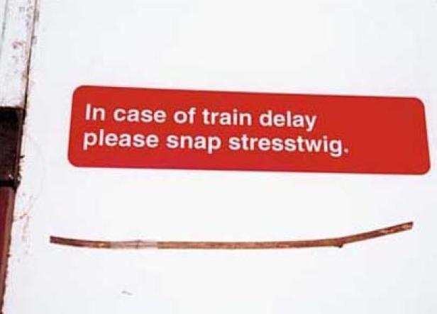 Ein Schild mit der Aufschrift „In case of train delay please snap stresstwigg“ und einem Zweig darunter.