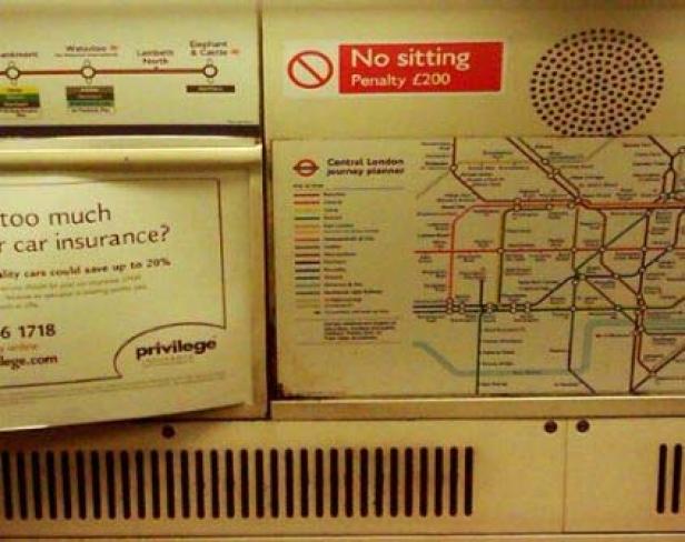 Im Inneren einer Londoner U-Bahn sind ein Liniennetzplan und eine Werbung für eine Autoversicherung zu sehen.