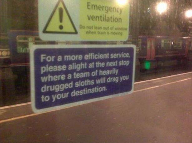 Ein Schild auf einem Bahnsteig weist darauf hin, dass man am nächsten Halt von Faultieren zu seinem Ziel gezogen wird.