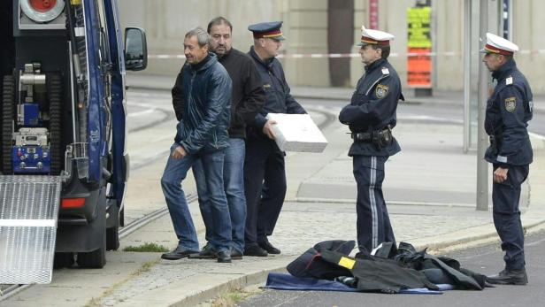 Polizisten untersuchen einen verdächtigen Gegenstand neben einem Lieferwagen.