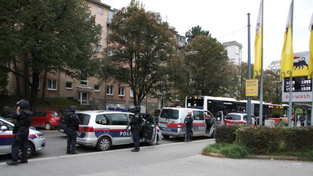 Mehrere Polizeibeamte und Einsatzfahrzeuge stehen an einer Straße in der Nähe einer Tankstelle.