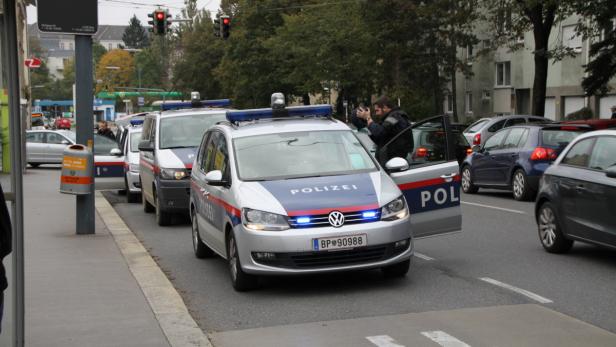 Mehrere Einsatzfahrzeuge der Polizei stehen auf einer Straße in Wien.