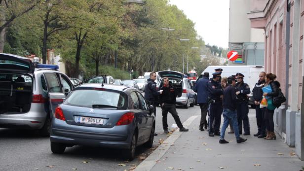 Polizeibeamte stehen neben einem blauen Auto auf einer Straße.
