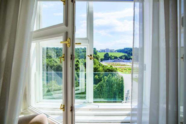 Blick aus einem Fenster auf Schloss Schönbrunn und den Garten in Wien.