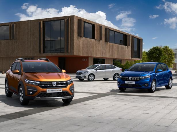 Drei Dacia-Modelle, darunter ein Sandero Stepway, stehen vor einem modernen Gebäude.