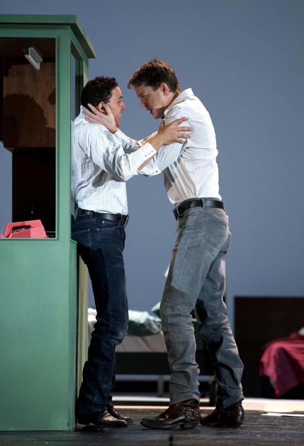 Zwei Männer in Hemden und Jeans stehen sich auf einer Bühne gegenüber.